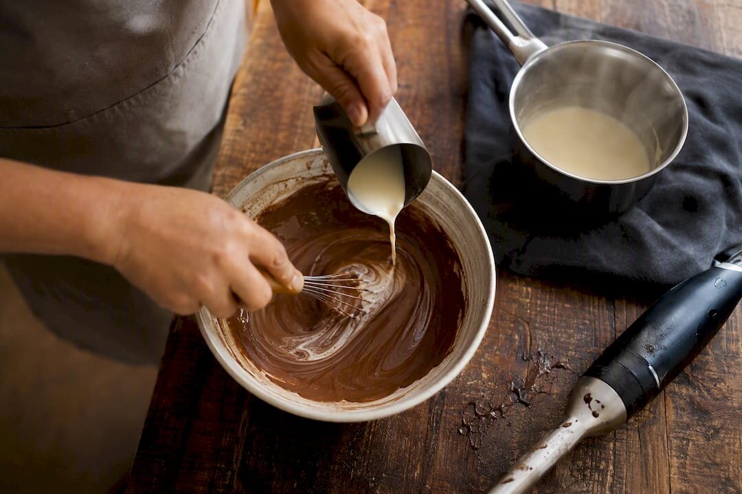 Manos arreglando una ganache rota con nata y una batidora