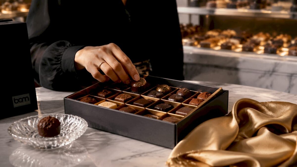 Surtido de bombones en caja de regalo abierta con guía de sabores